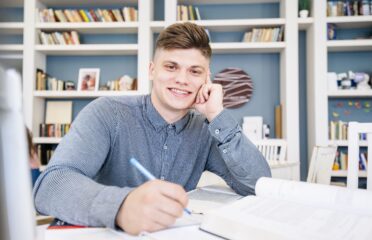 Student sitting with books pen library 1